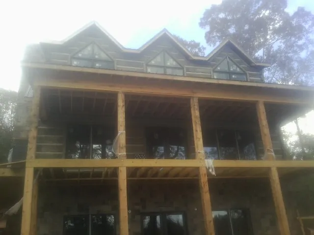 Dormers and porch framing on a large log home under construction — Roof Coating work by our crew in Lillian
