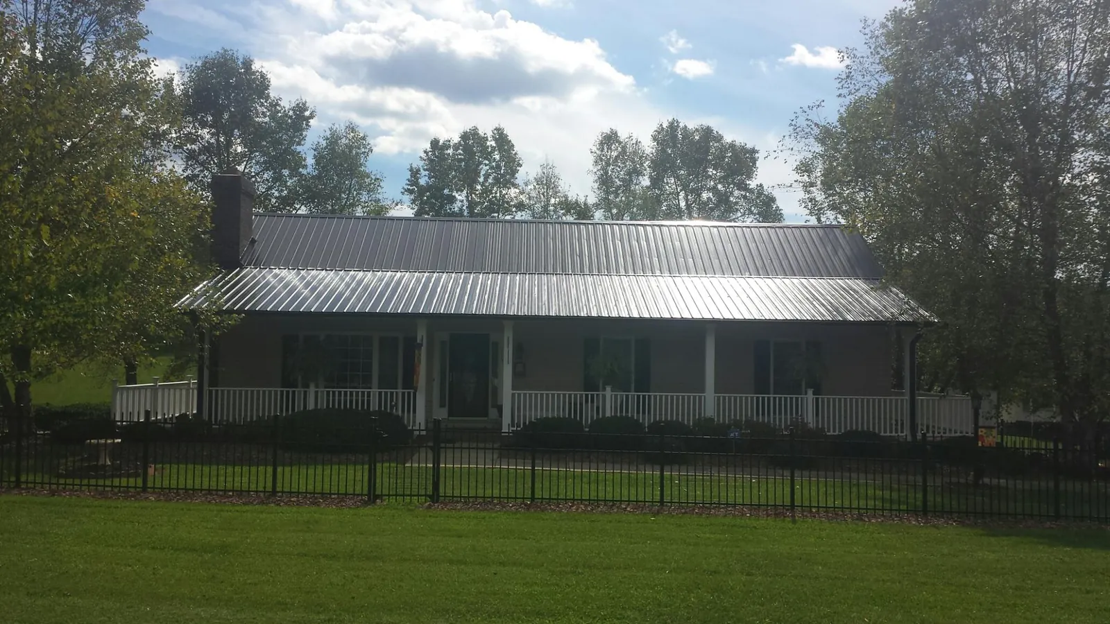 Gray metal roof on a brick ranch with a full width front porch — Gutter Guard Installation work by our crew in Lillian