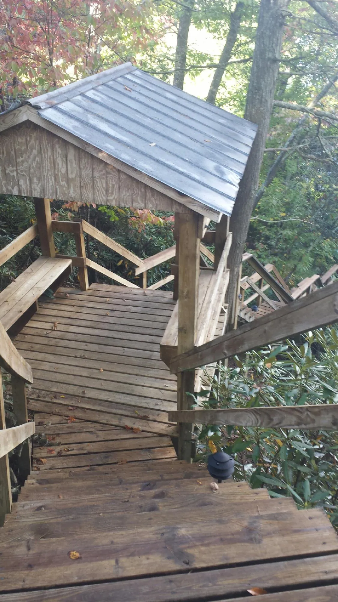 Metal roofed shelter over wooden steps on a wooded walkway — Skylight Repair & Installation work by our crew in Lillian